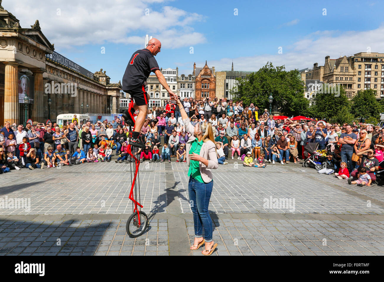 Artiste de rue d'effectuer sur un monocycle au cours de l'Edinburgh Fringe Festival et impliquant un membre du public, le tertre Banque D'Images