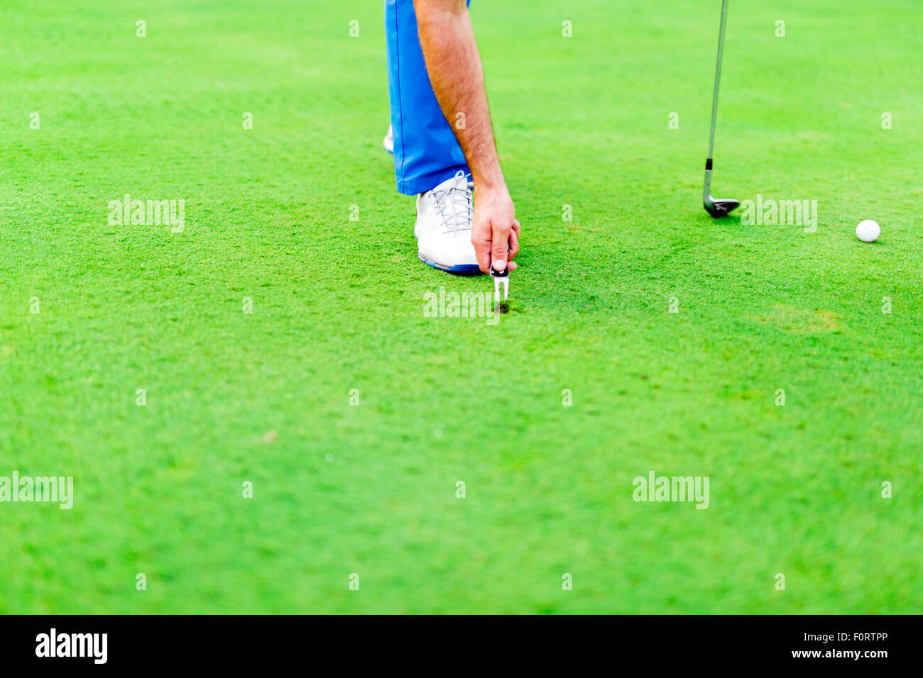 Joueur de golf réparation divot sur une surface d'herbe verte Banque D'Images