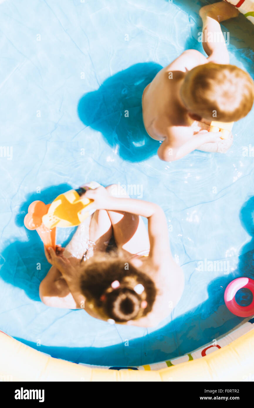 De jeunes enfants jouant avec des jouets à l'intérieur d'une piscine gonflable en été Banque D'Images