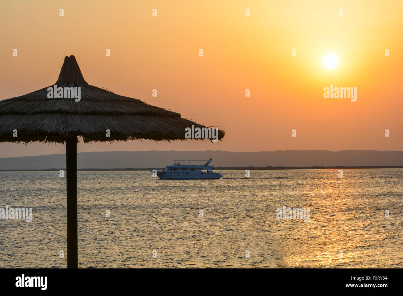 Motor Yacht voyageant passé île sur une mer tropicale au lever du soleil Banque D'Images
