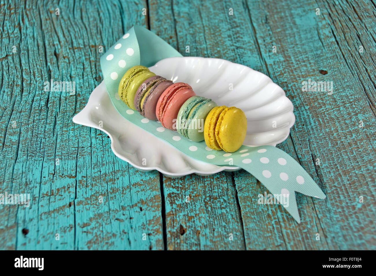 Rangée de colorful macarons français blanc sur plaque et coquillage polka dot ruban. Banque D'Images