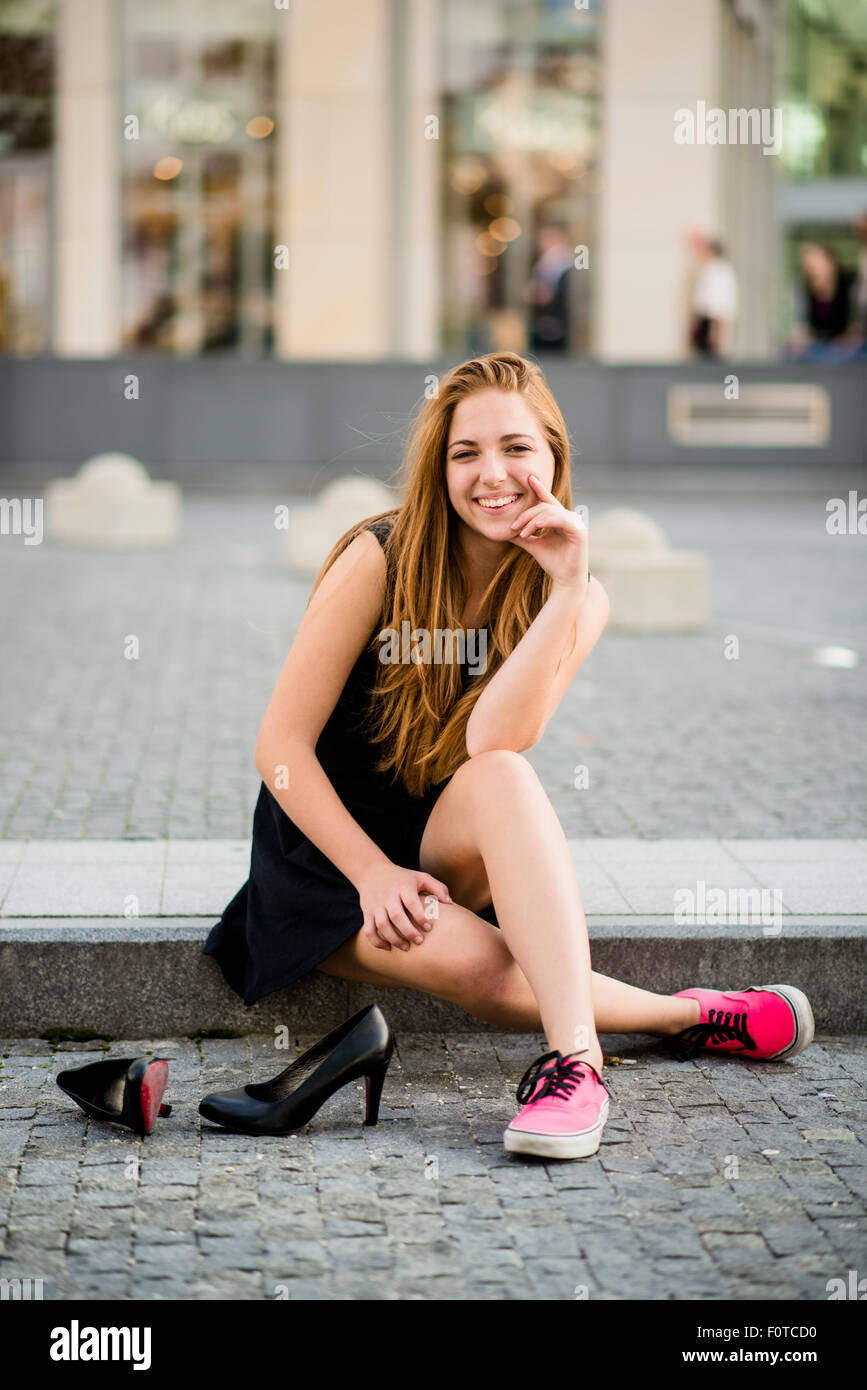 Jeune femme sur rue dans sneakers holding High heels shoes Banque D'Images