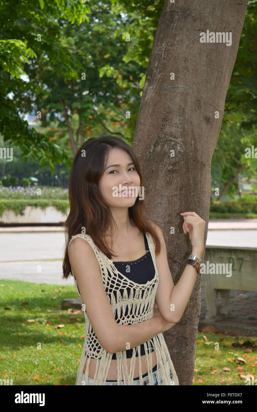Thai woman smiling at the park à côté d'un arbre Banque D'Images