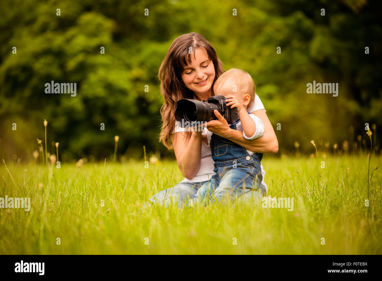 Mère montrant son bébé photos sur votre appareil photo reflex numérique à l'extérieur Banque D'Images