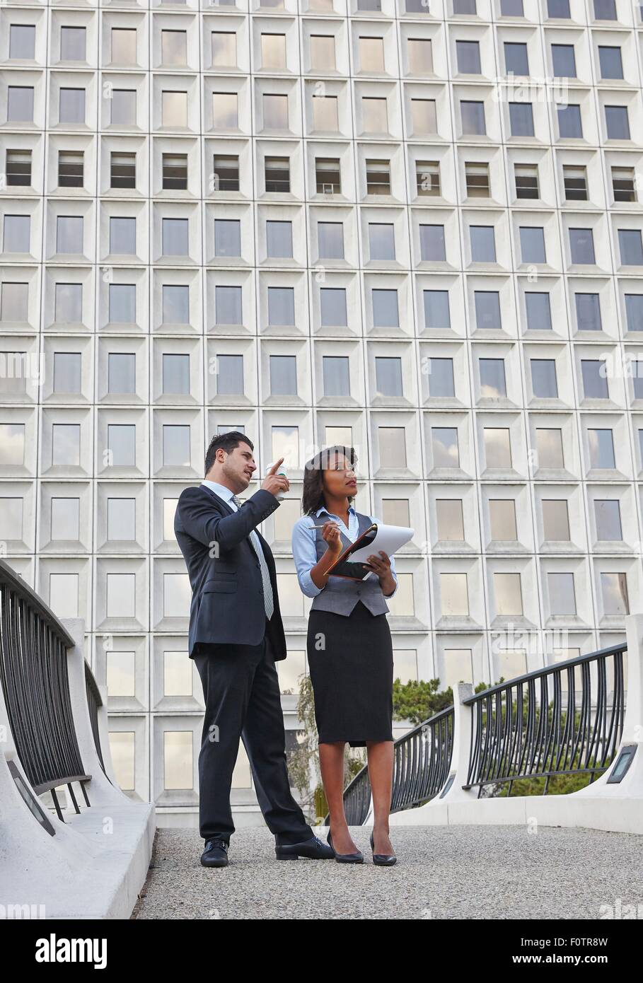 Les gens d'affaires parler debout tenant la paperasserie, pointant vers le haut et à la Banque D'Images
