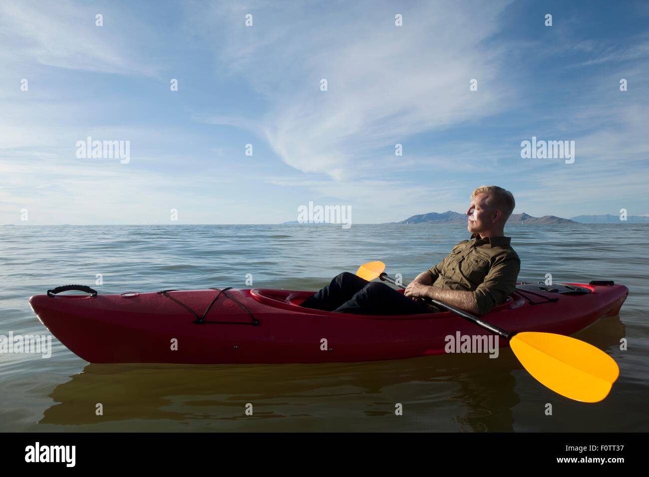 Vue latérale du jeune homme en kayak sur les palettes de rétention d'eau, les yeux clos, Grand Lac Salé, Utah, USA Banque D'Images