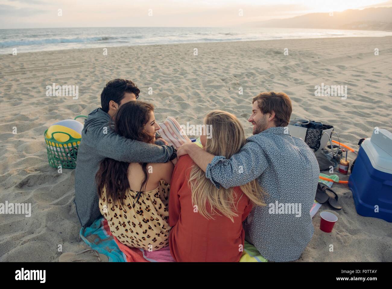 Groupe d'amis ayant pique-nique sur plage, vue arrière Banque D'Images