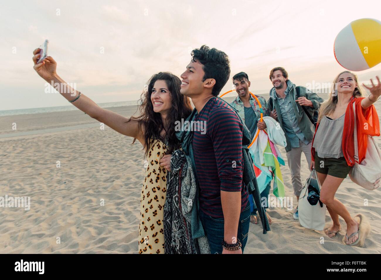 Groupe d'amis à marcher le long beach, young couple taking self portrait with smartphone Banque D'Images