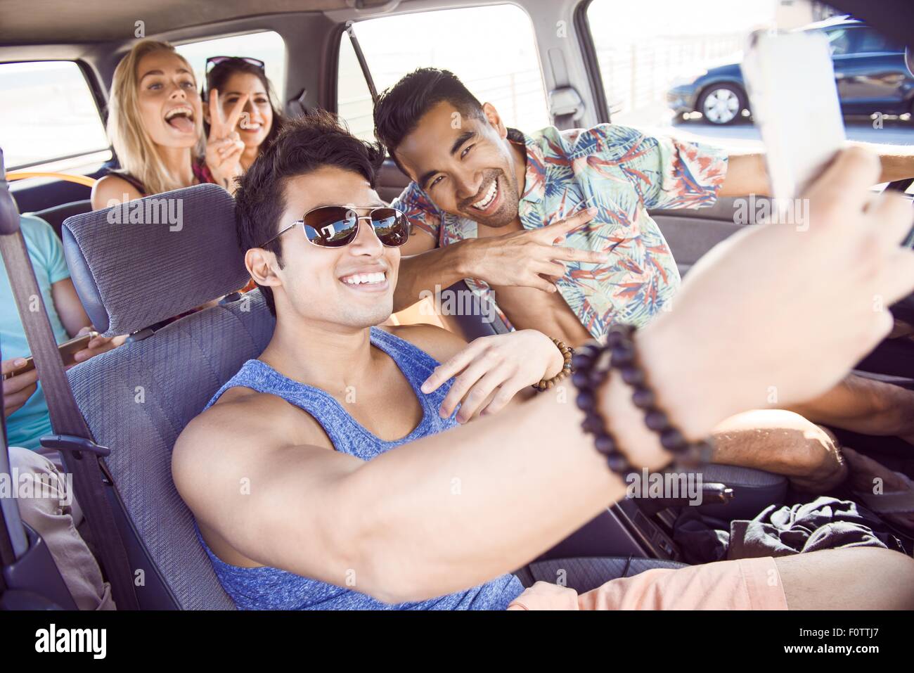 Groupe d'amis assis dans la voiture, taking self portrait with smartphone, rire Banque D'Images