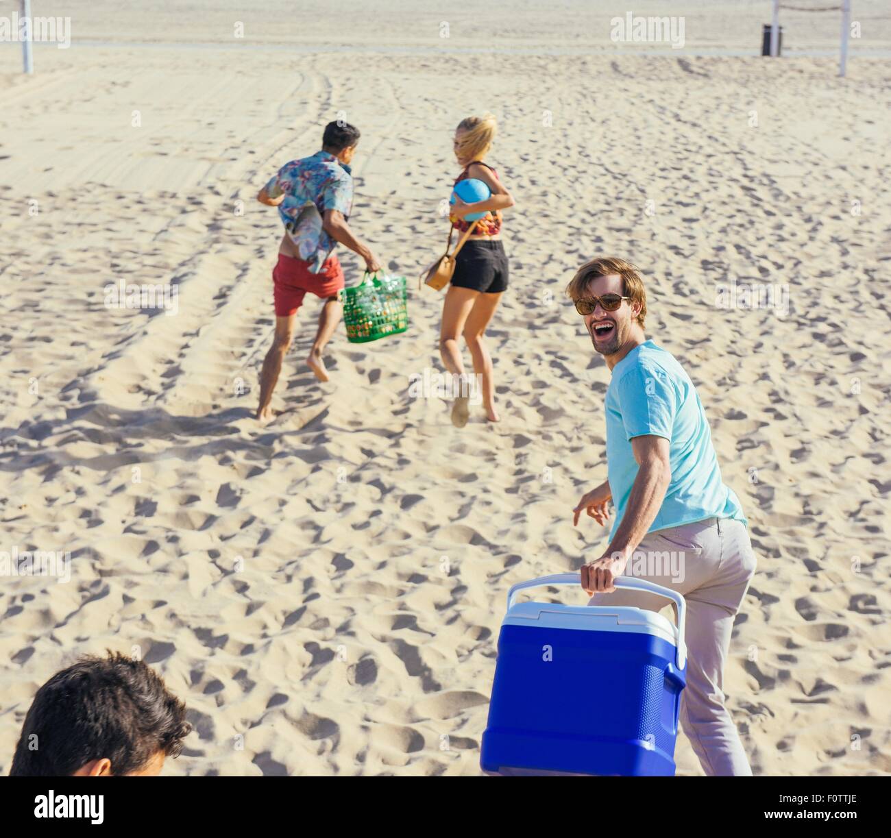 Groupe d'amis walking on beach, prêt pour un pique-nique Banque D'Images
