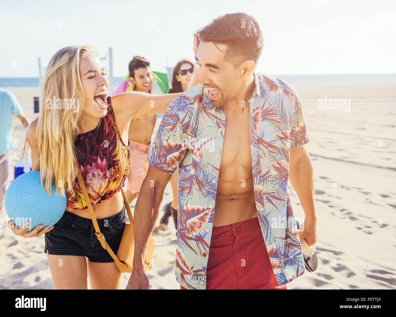 Groupe d'amis walking on beach, prêt pour un pique-nique Banque D'Images