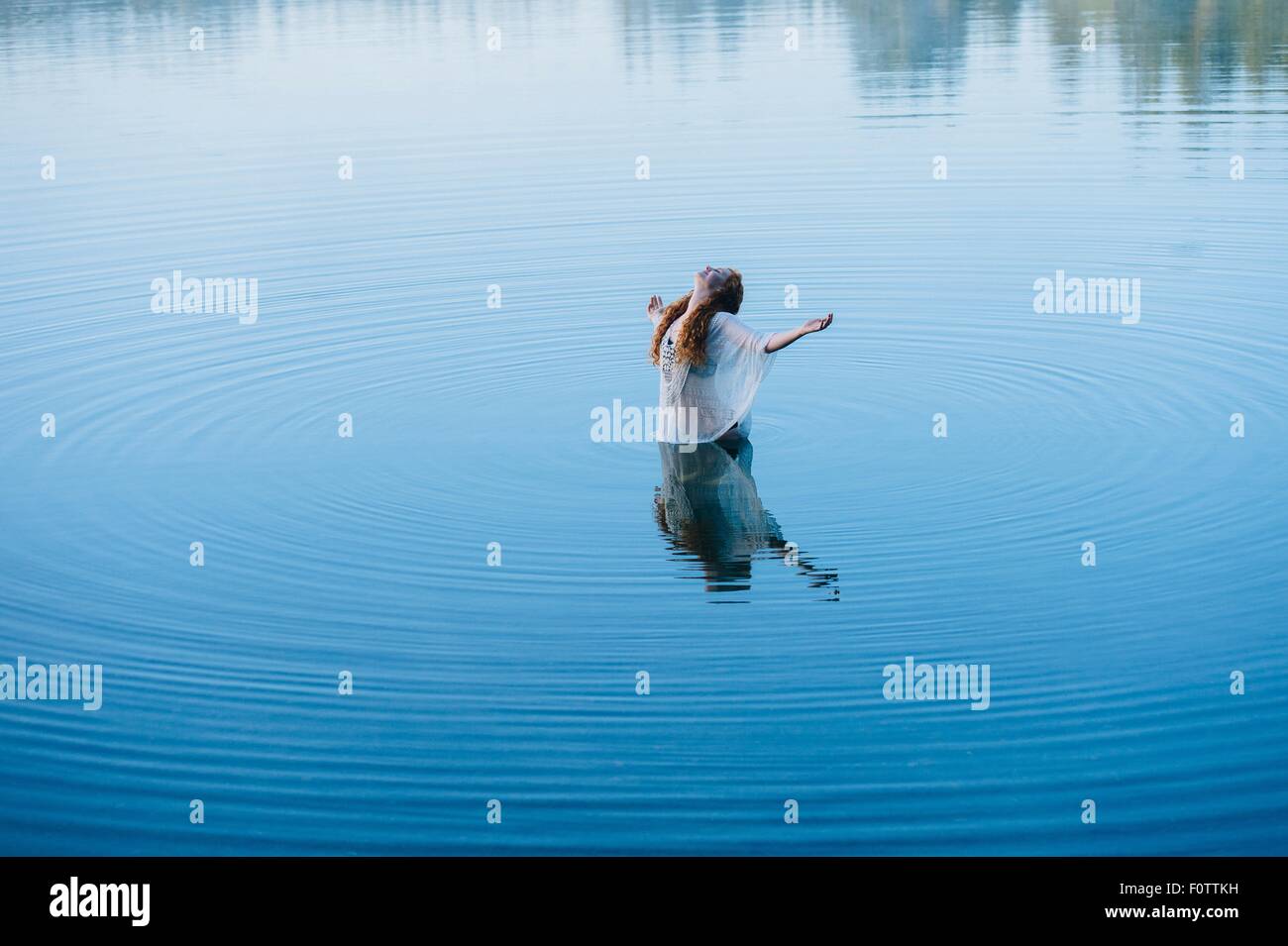 Jeune femme debout au milieu du lac ondulations avec les bras ouverts et la tête en arrière Banque D'Images