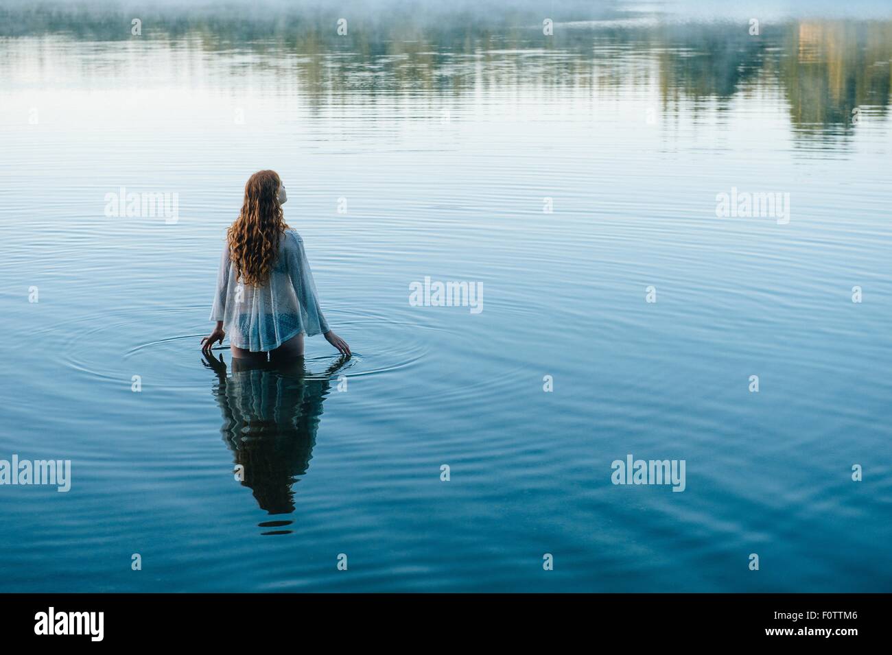 Vue arrière du jeune femme en surface ondulée du lac avec ses doigts Banque D'Images