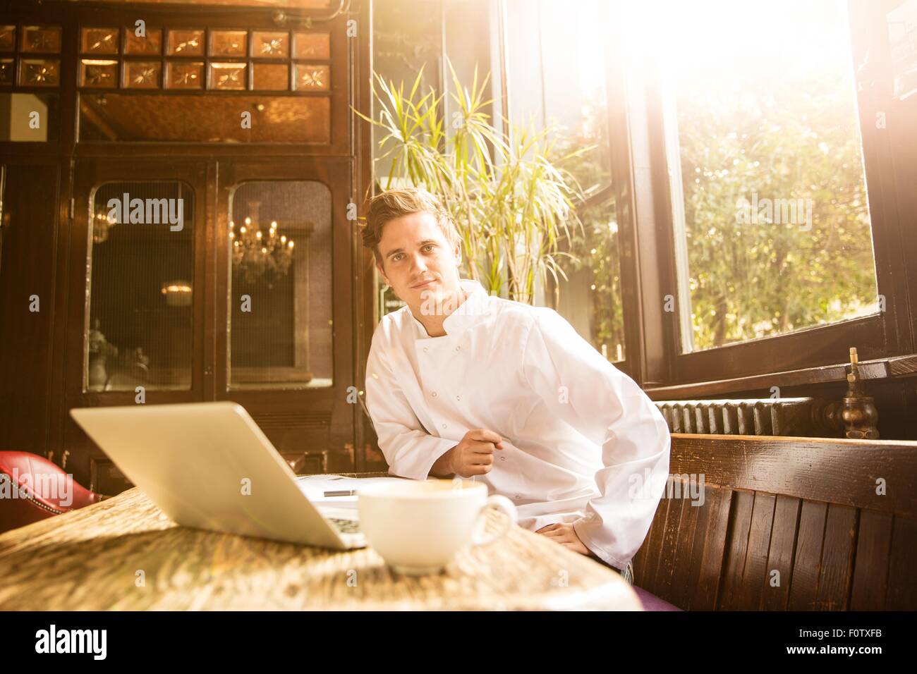 Jeune chef assis au travail looking at camera Banque D'Images