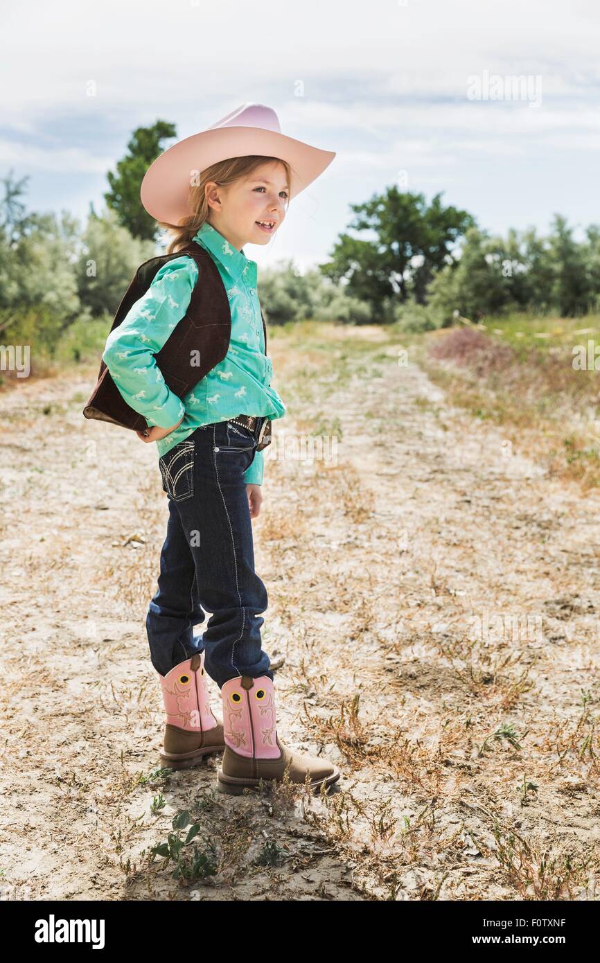 Girl wearing cowboy hat et bottes sur le chemin Banque D'Images