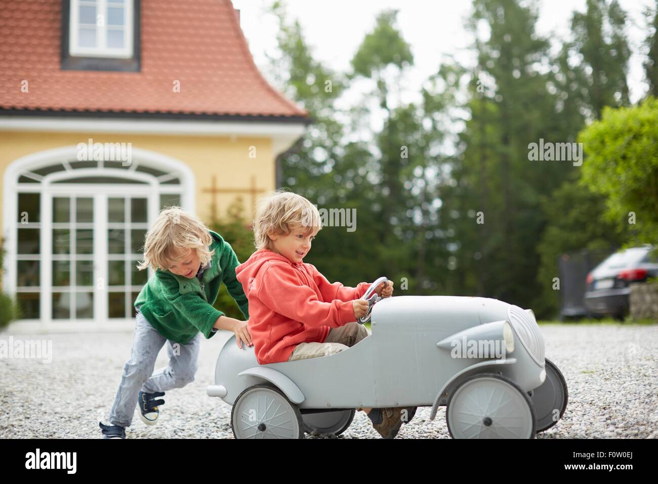 Deux garçons jouant avec vintage toy voiture en face de la maison Banque D'Images