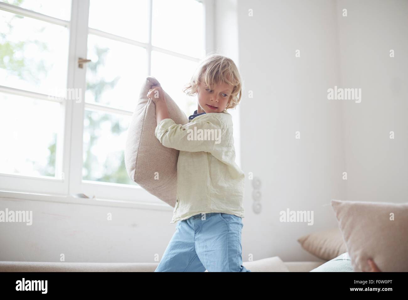 Boy holding pillow prépare à lancer Banque D'Images