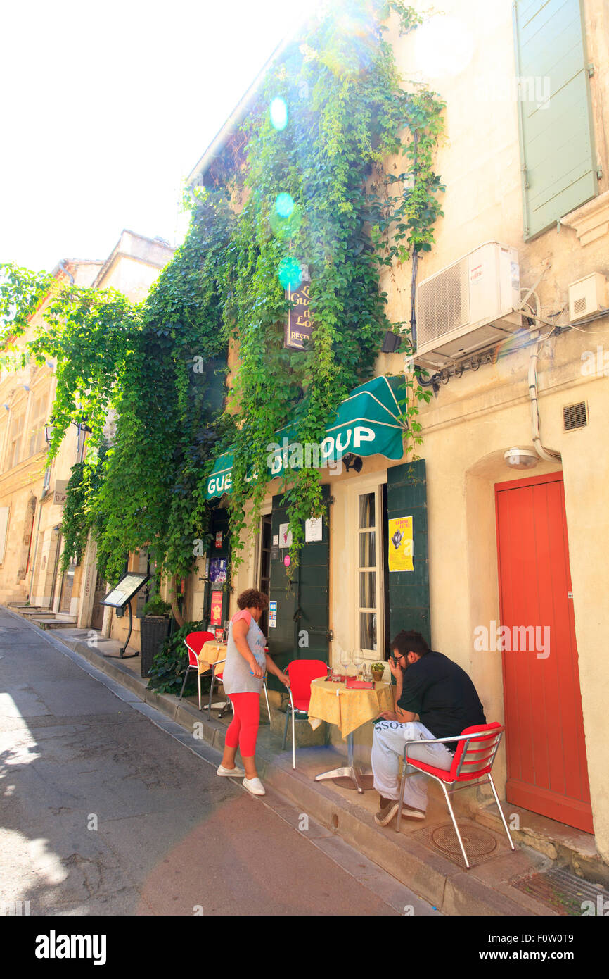 Le client est assis à une table de café perché sur un étroit trottoir en Arles France Banque D'Images