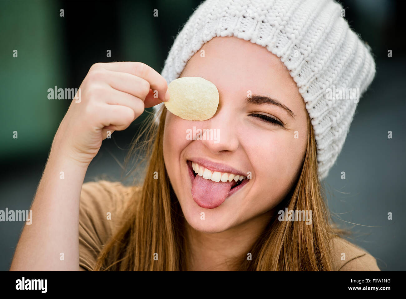 Adolescentes en cap s'amusant avec les chips de pomme de terre sur les yeux en plein air street Banque D'Images