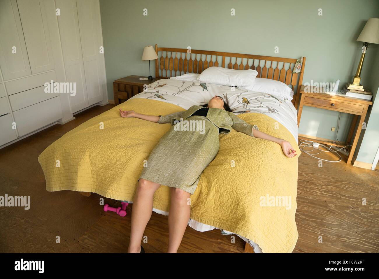 Mid adult woman lying on bed with arms open Banque D'Images