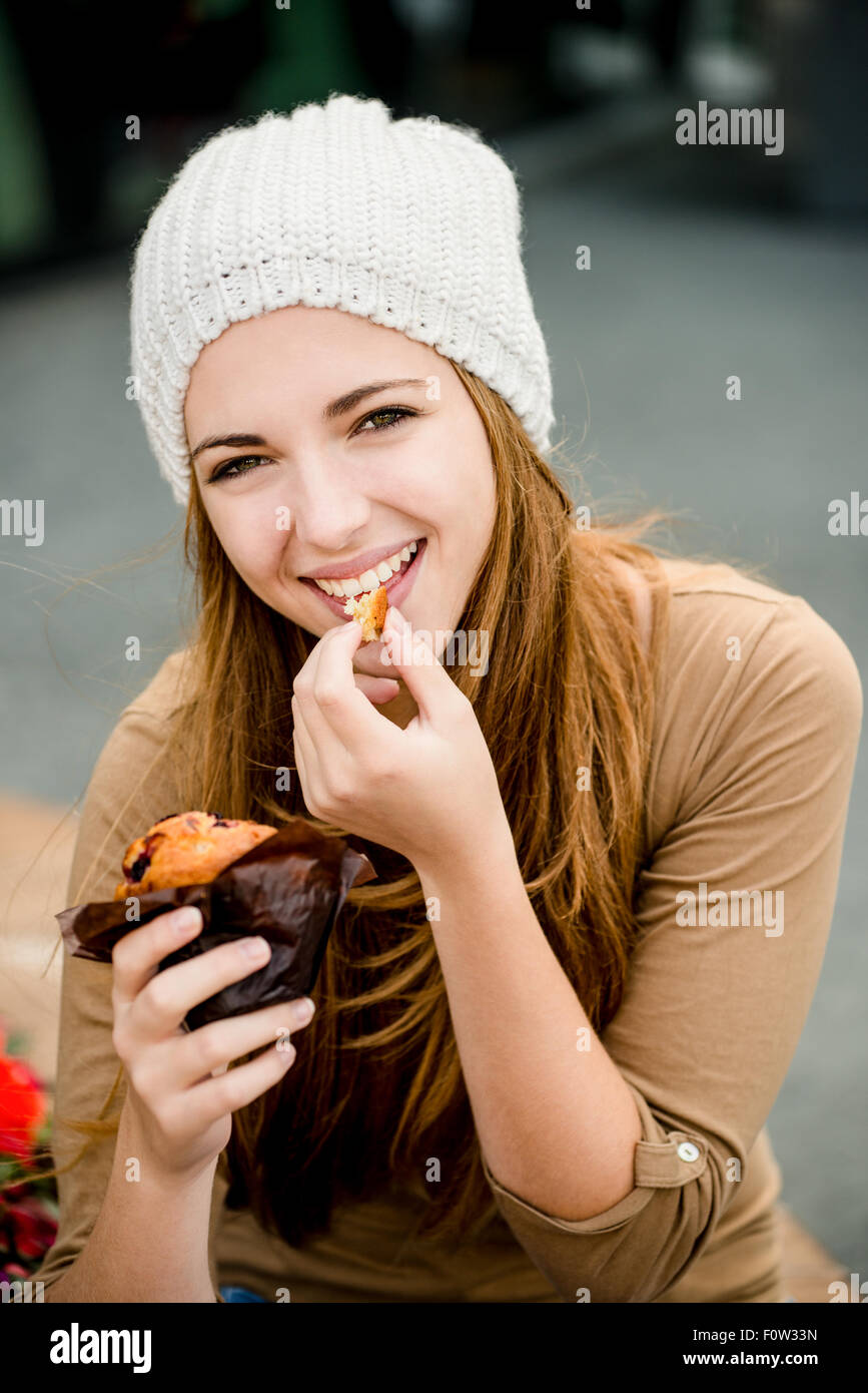 Jeune femme - adolescent à cap de manger en plein air, rue de muffin Banque D'Images