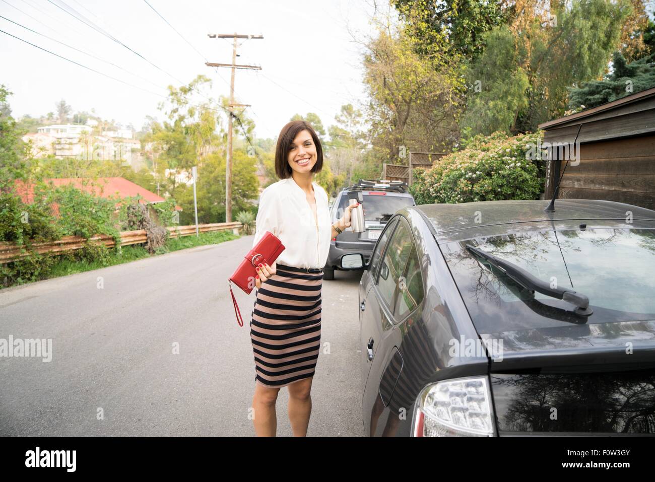 Portrait of businesswoman à côté de voiture sur la rue de banlieue Banque D'Images