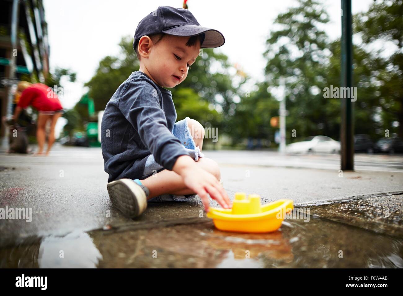 Boy Playing with toy voile sur l'eau sur la chaussée Banque D'Images