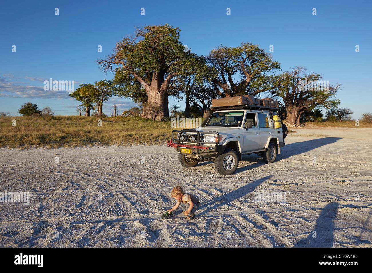 Garçon jouant par véhicule, Parc National de Nxai Pan, Désert du Kalahari, Afrique Banque D'Images