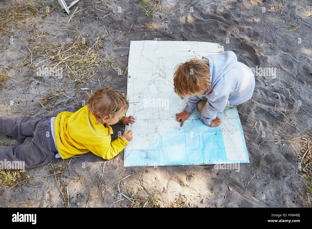 Les garçons reading map sur gravier Banque D'Images