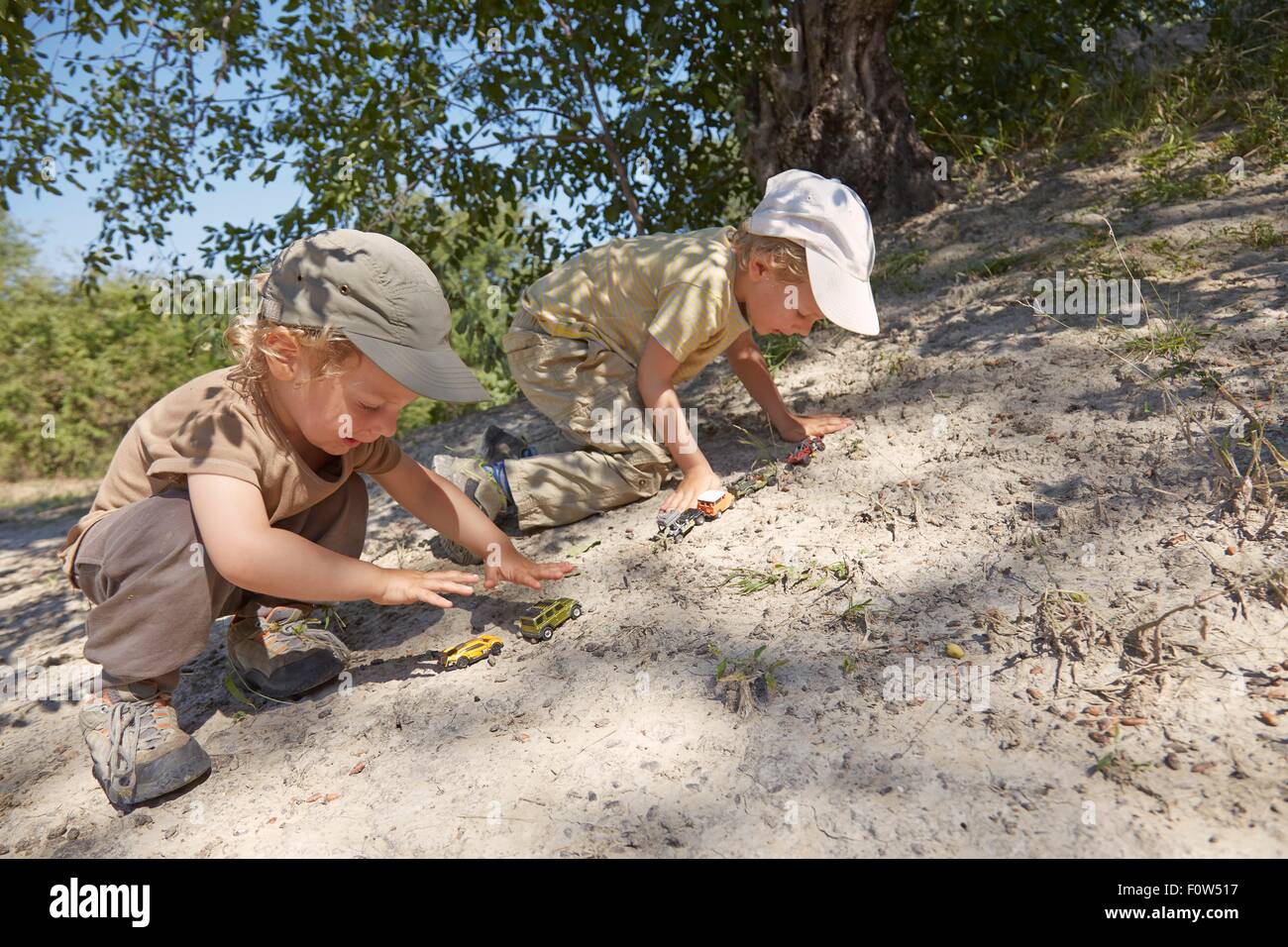 Deux jeunes garçons, Playing with toy cars on sand Banque D'Images