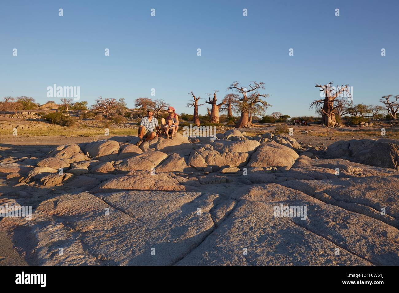 Family sitting on rocks, looking at view, Gweta, makgadikgadi, Botswana Banque D'Images