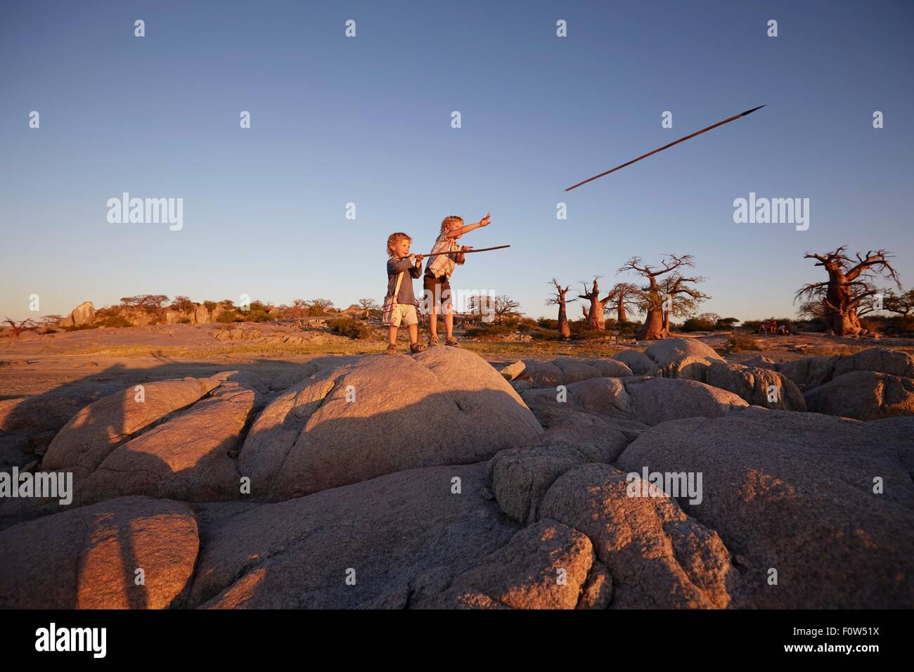 Deux jeunes garçons debout sur la roche, de lancer des piques, Gweta, makgadikgadi, Botswana Banque D'Images