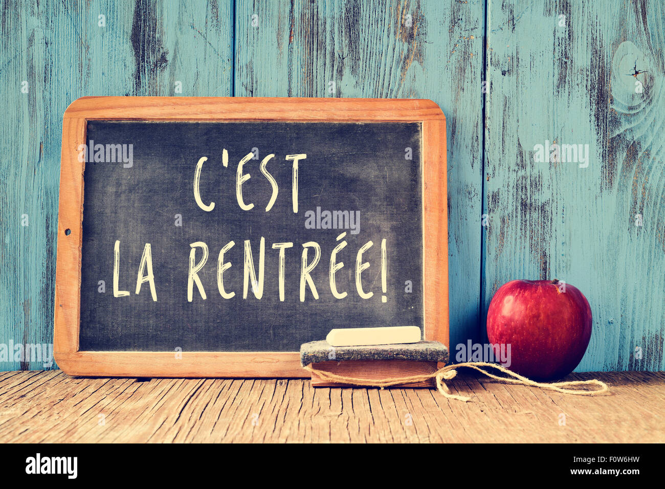 Un tableau sur le texte cest la rentrée, le retour à l'école en français écrit en C, un morceau de craie, une gomme et une pomme rouge Banque D'Images