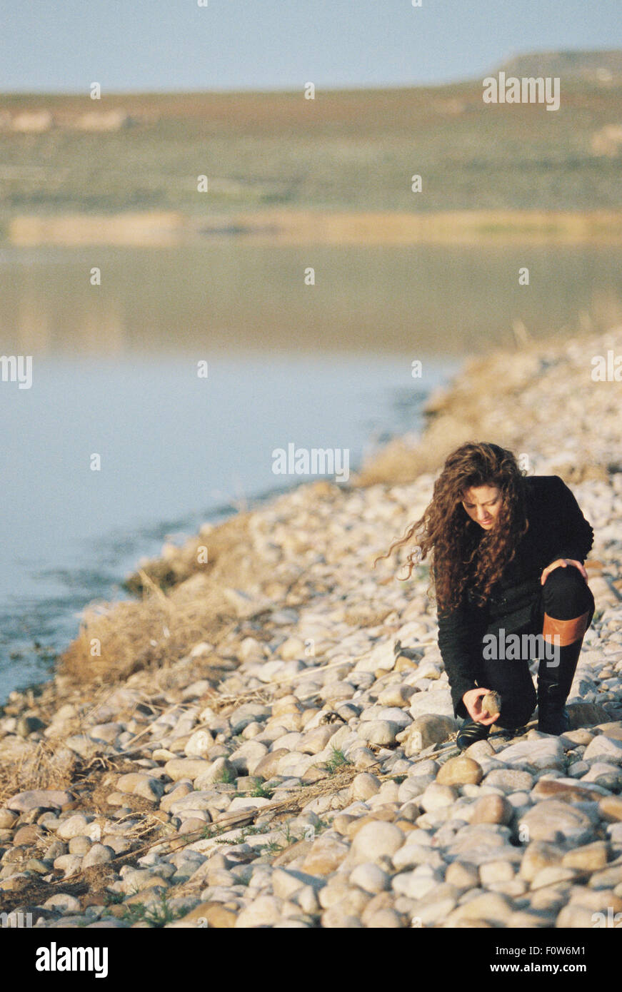 Une femme la collecte des cailloux sur la rive d'un lac. Banque D'Images