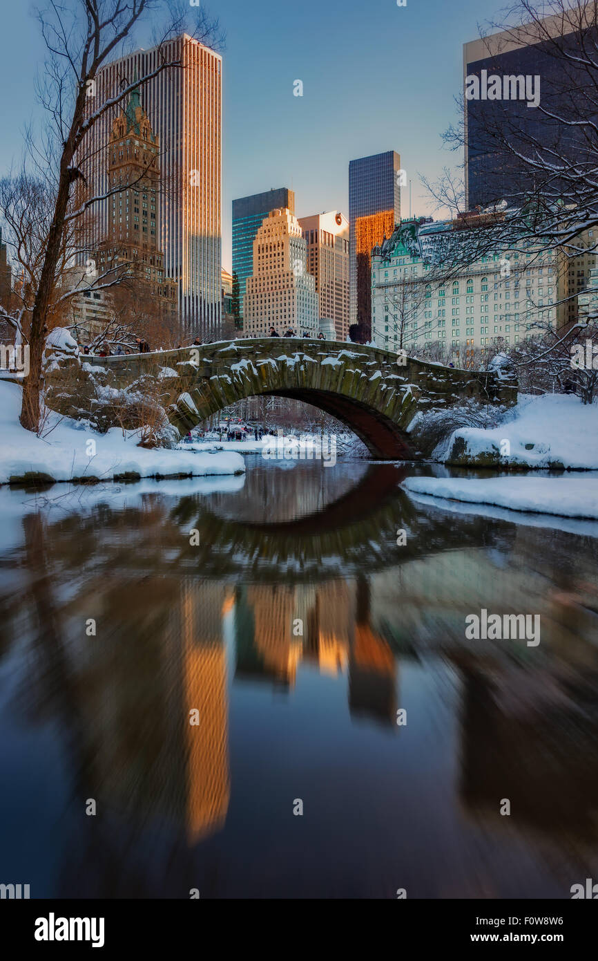 Gapstow Bridge reflète dans l'étang pendant le coucher du soleil à Central Park à New York après une tempête de neige. Banque D'Images
