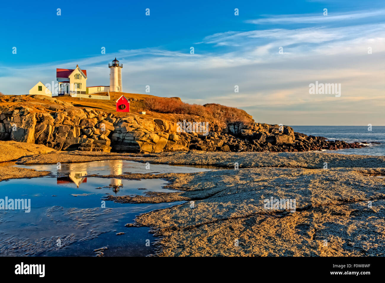 Phare de Nubble à Cape Neddick dans York Maine reflétée sur la flaque gelée par un froid mais glorieuse coucher du soleil d'après-midi. Banque D'Images