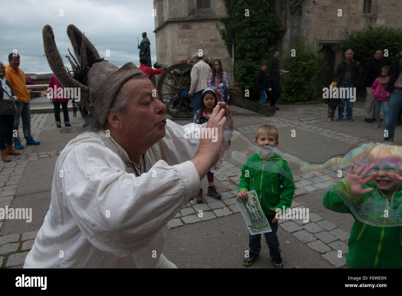 Un artiste de rue souffle des bulles de savon géantes pour amuser les enfants au Château de Hohenzollern, Bade-Wurtemberg, Allemagne Banque D'Images