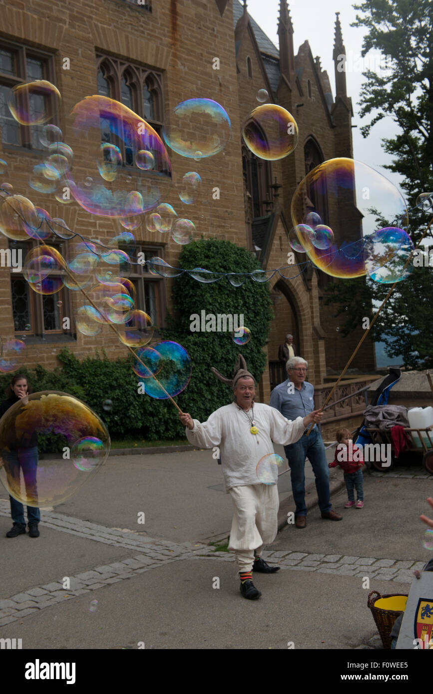 Un artiste de rue souffle des bulles de savon géantes pour amuser les enfants au Château de Hohenzollern, Bade-Wurtemberg, Allemagne Banque D'Images