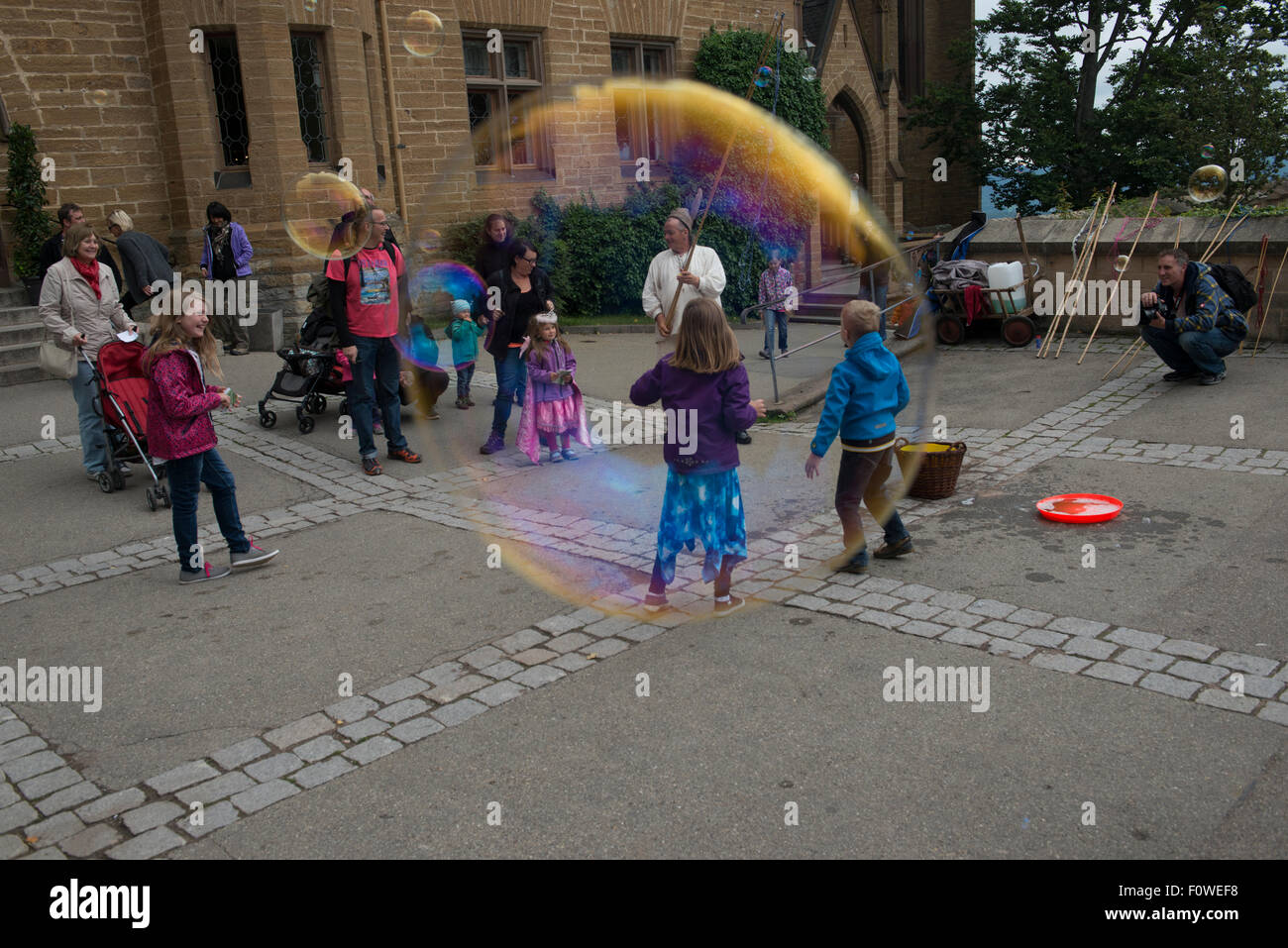 Un artiste de rue souffle des bulles de savon géantes pour amuser les enfants au Château de Hohenzollern, Bade-Wurtemberg, Allemagne Banque D'Images