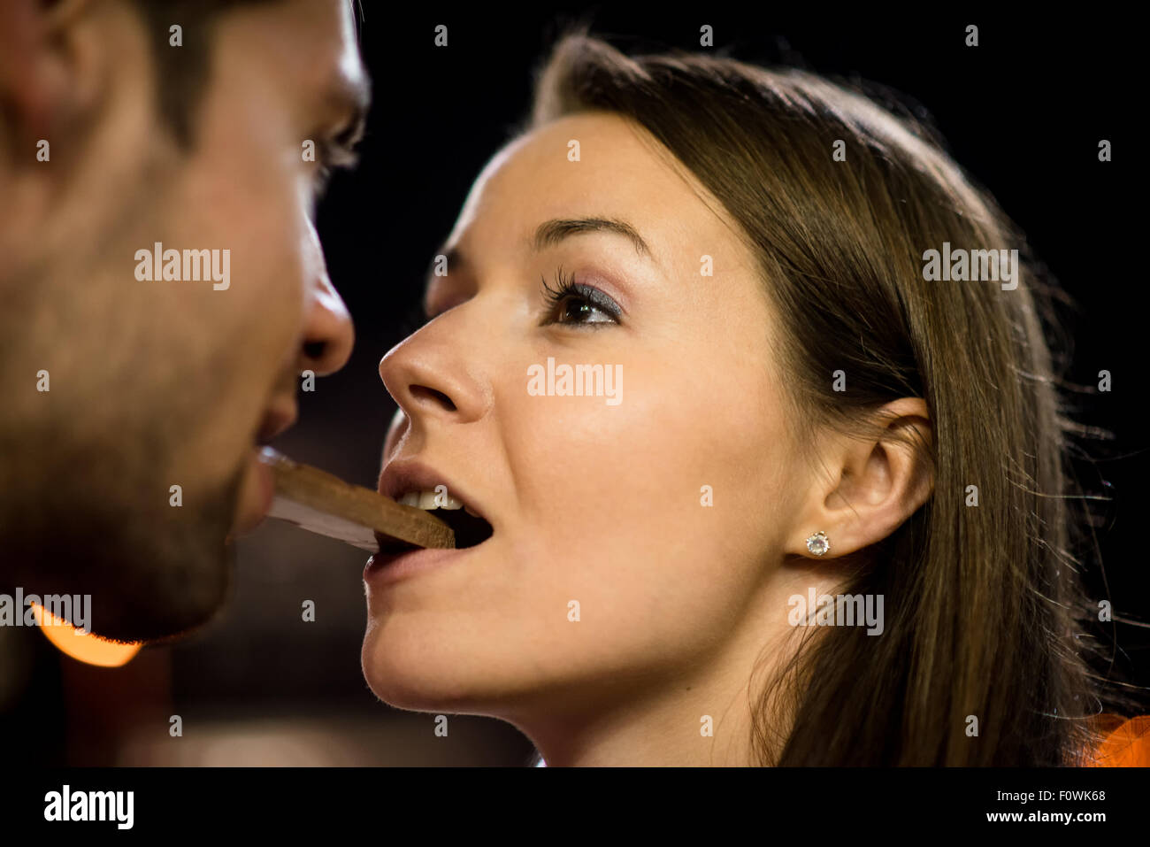 Jeune couple de manger ensemble un morceau de chocolat - dans la rue la nuit Banque D'Images