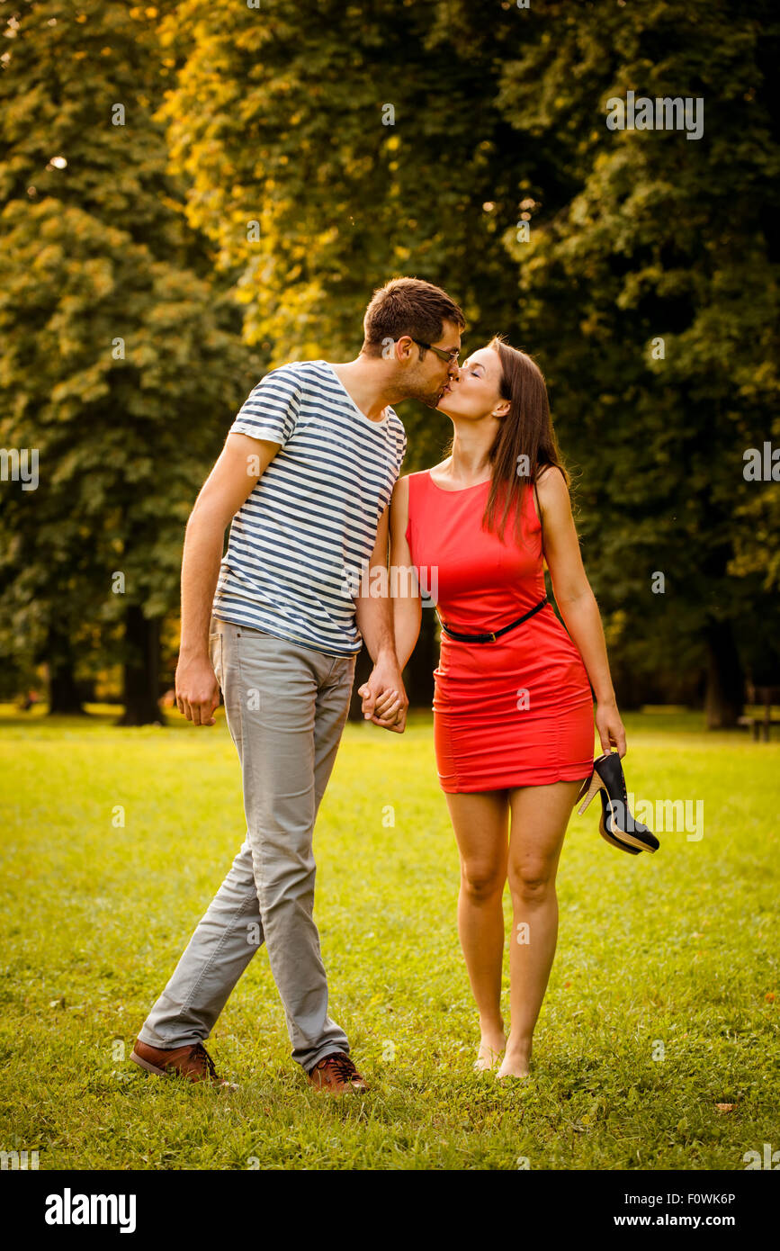Couple en train de marcher et de s'embrasser dans la nature - femme est pieds nus holding High heels shoes Banque D'Images