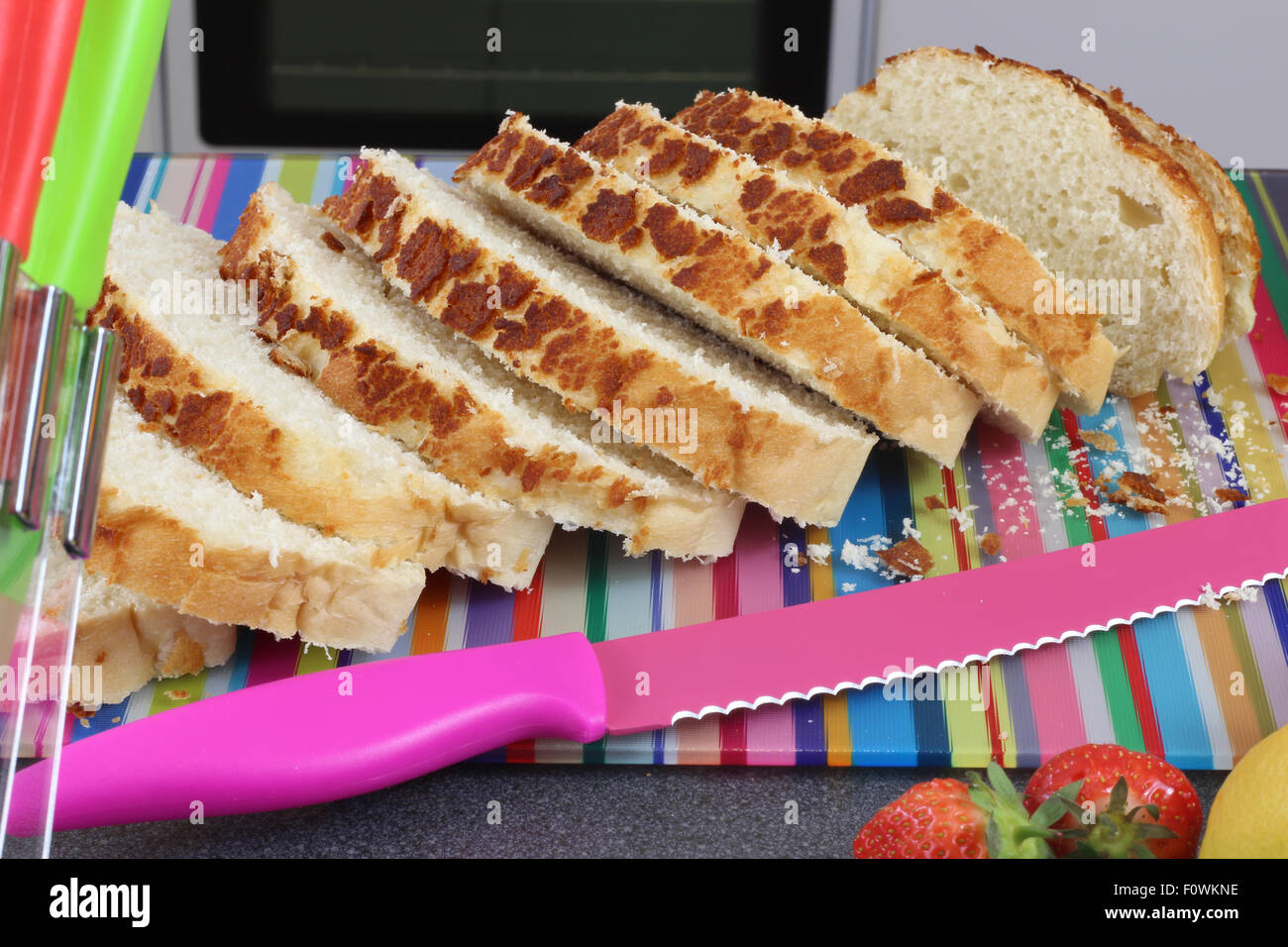 Scène cuisine colorée avec des tranches de pain frais sur une planche à découper. Banque D'Images