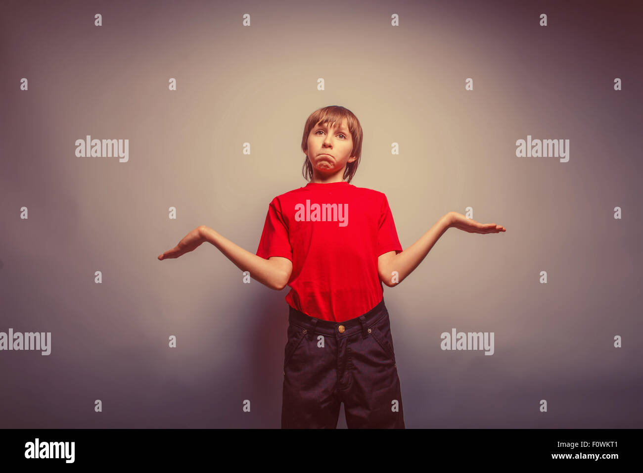 L'adolescent garçon apparition dans un chandail rouge propagation ses bras Banque D'Images