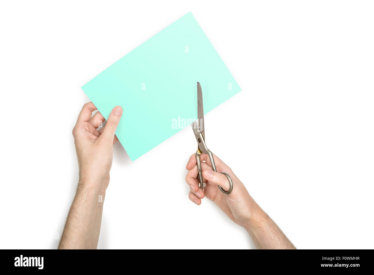 Une femme coupe une feuille de papier vert métallique à l'aide de ciseaux, isolé sur fond blanc Banque D'Images