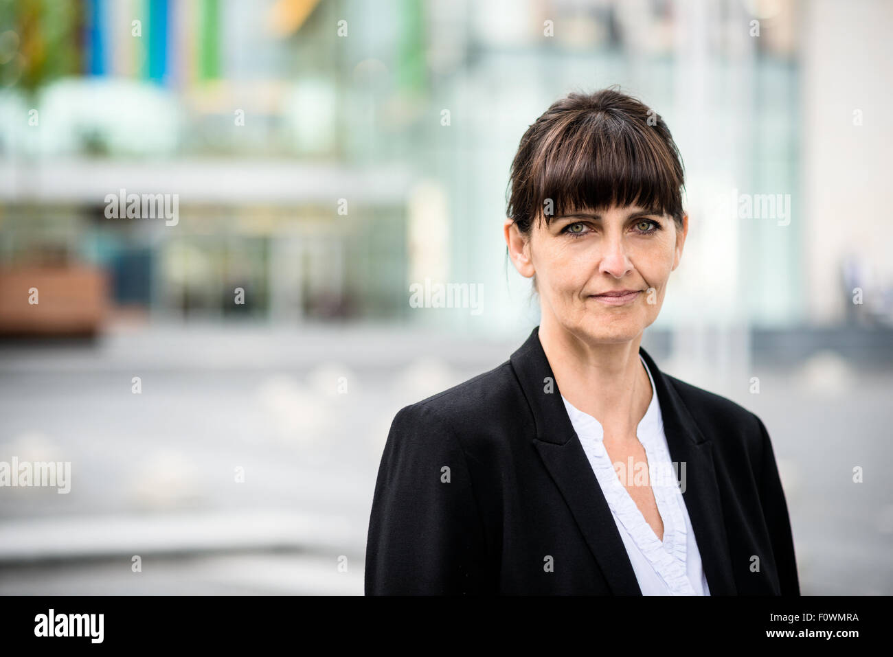 De l'extérieur confiant senior business woman avec immeuble de bureaux modernes en arrière-plan Banque D'Images