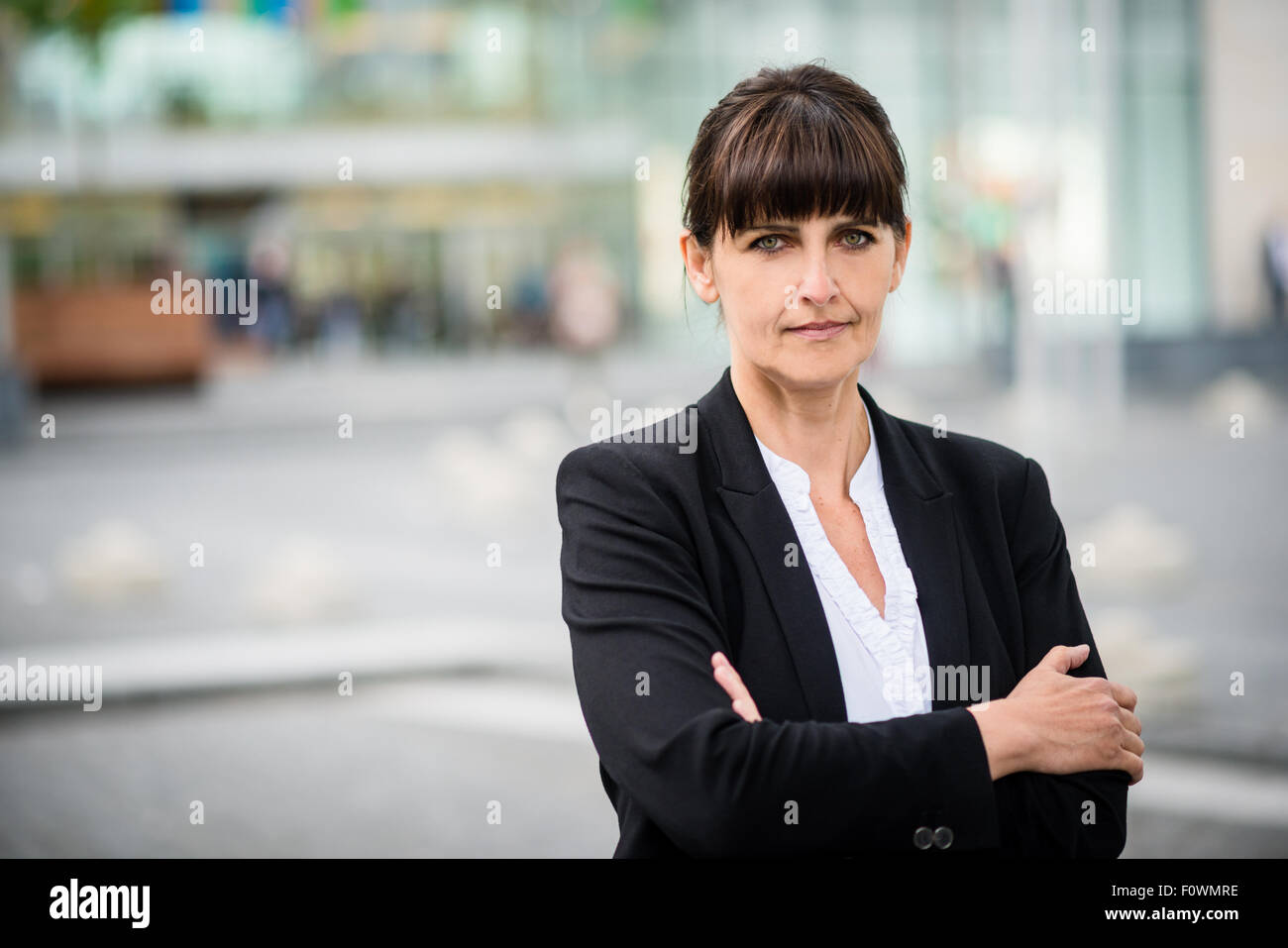 Exterior portrait of senior business woman standing in street avec les mains croisées Banque D'Images
