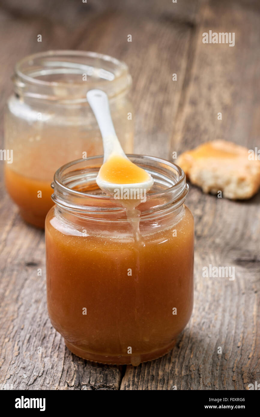 Sauce au caramel dans un bocal en verre sur un fond de bois Banque D'Images