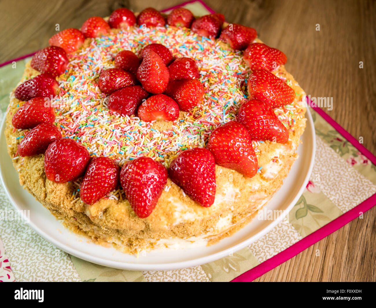 Gâteau au miel avec des fraises sur table en bois rouge Banque D'Images