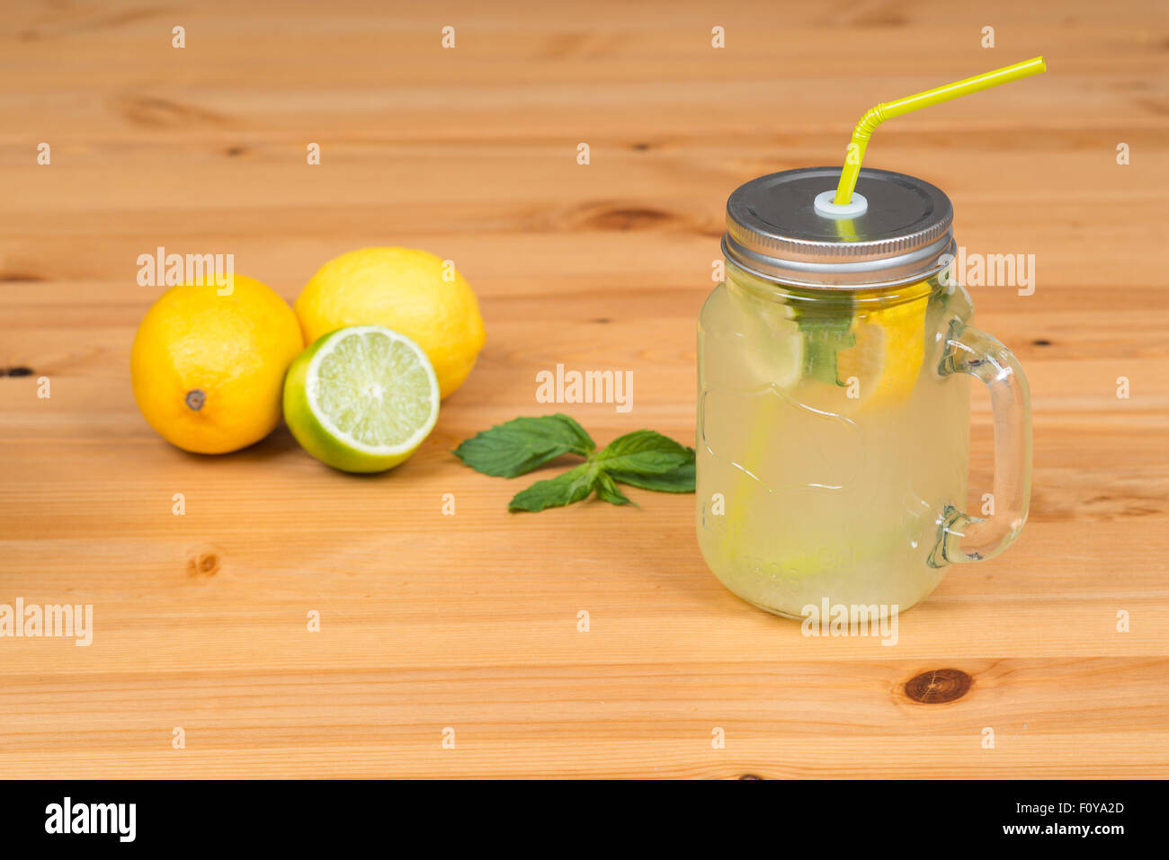 La limonade avec deux citrons, un tilleul et menthe, fond en bois Banque D'Images