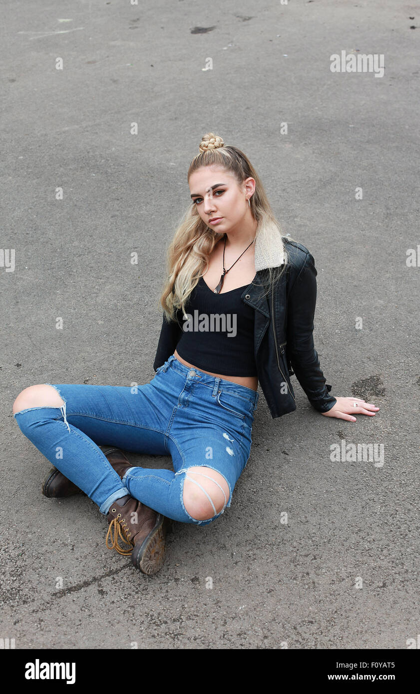 Teenage girl sitting difficiles, les jambes croisées sur le béton Banque D'Images